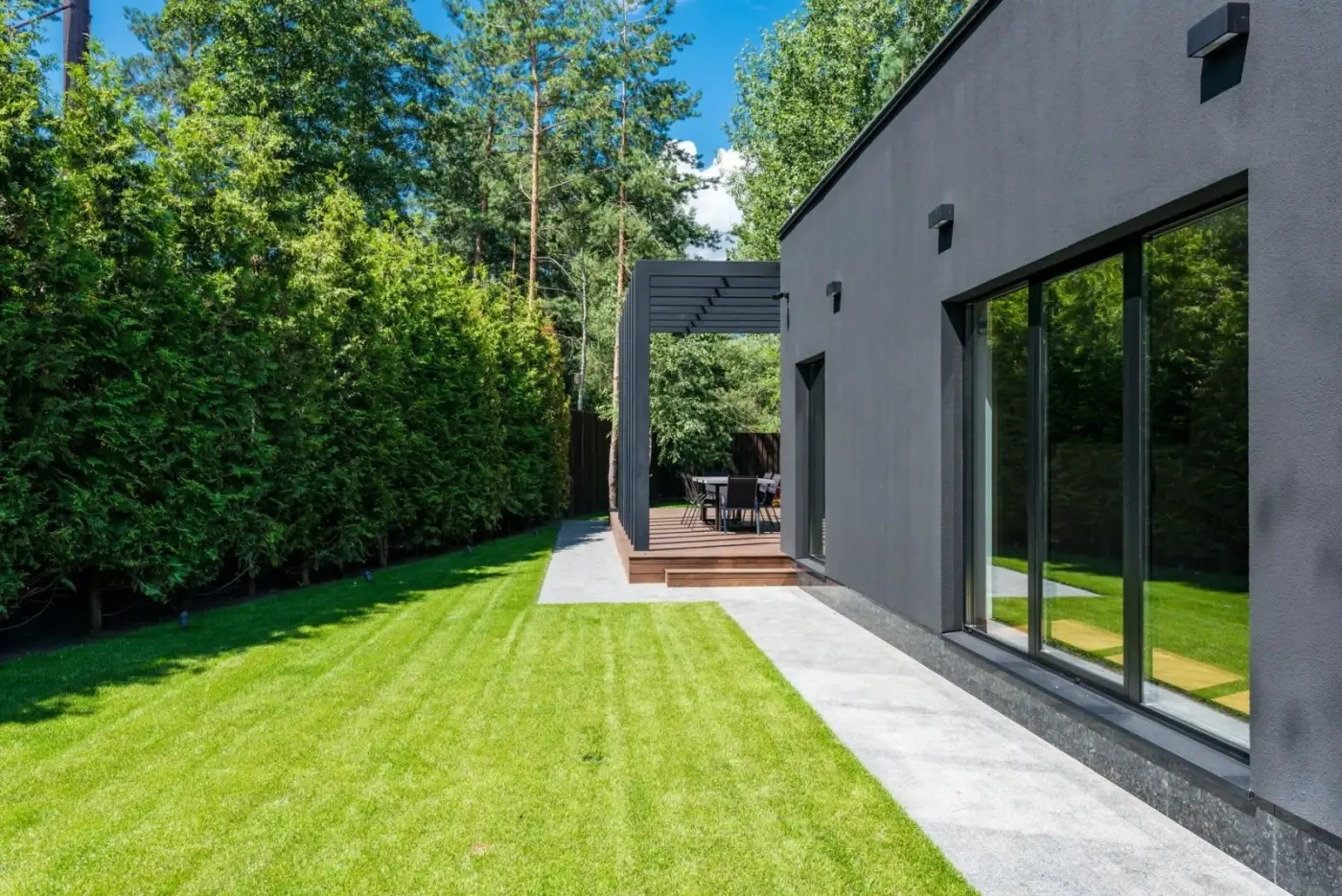 A neatly mown lawn and clipped hedge beside a modern home